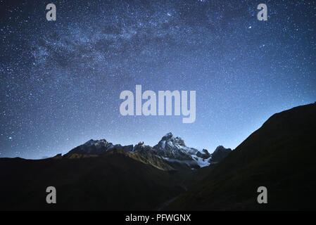 Paesaggio notturno. Cielo stellato con la Via Lattea oltre le montagne. Montare Ushba alla luce della luna crescente. Principale crinale caucasico. Zemo Svaneti, Ge Foto Stock