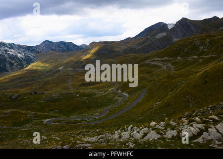 Una strada che conduce attraverso prati rocciosi e colline in montagna Foto Stock