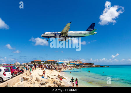 Un volo Jetblue passa al di sopra di Maho Beach e decine di turisti appena prima di atterrare all'aeroporto internazionale Principessa Juliana in Saint Martin. Foto Stock