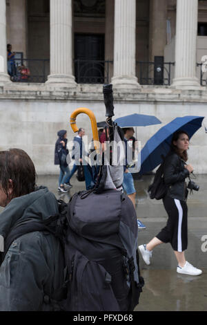 Pedoni e ombrelloni durante un improvviso acquazzone in Trafalgar Square, il 13 agosto 2018, a Londra, in Inghilterra. Foto Stock