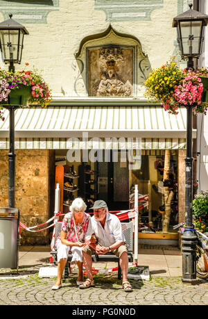 Due pensionati sedersi al di fuori di un negozio nel quartiere dello shopping di Fussen, Germania meridionale Foto Stock