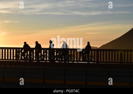 Sagome di un gruppo di ciclisti al tramonto Foto Stock