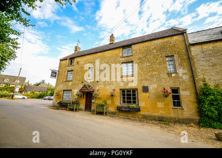 Gli agricoltori Arms pub, Guiting Power un piccolo villaggio del Gloucestershire in Cotswolds, Inghilterra, Regno Unito. Pub di campagna con cestelli appesi. Cotswold stone Foto Stock