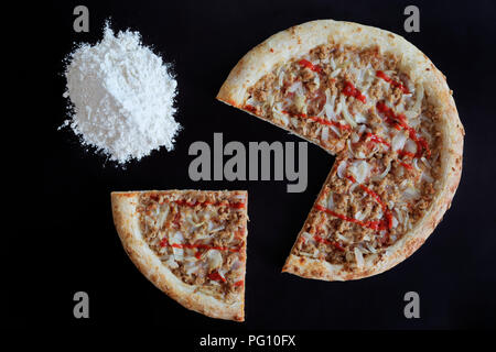 Tonno al forno la pizza e il palo di farina su sfondo nero Foto Stock