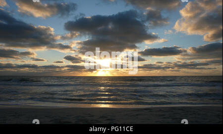 Intensamente colorati e drammatico tramonto nel vedere dalla spiaggia al crepuscolo come sun è l'impostazione Foto Stock