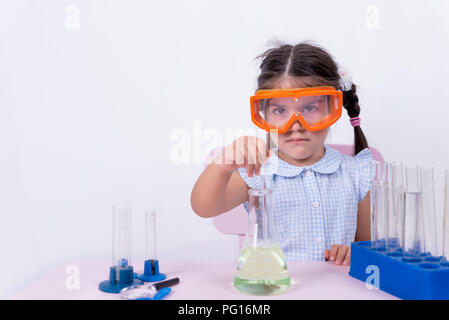 Grave carino bambina in uniforme scolastica suscita provetta o pallone da laboratorio.messa a fuoco selettiva e e il concetto di immagine Foto Stock