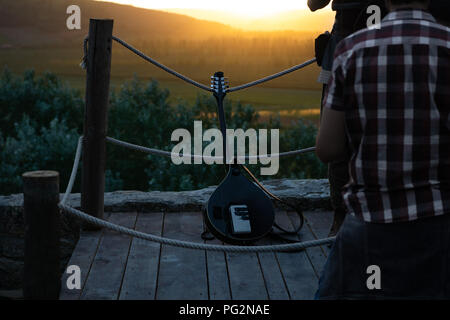 Strumento a corda appoggiata contro le corde sullo sfondo di un tramonto sul rotolamento campi verdi, alberi e colline Foto Stock