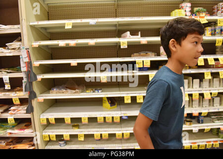 Honolulu, Hawaii. 23 Ago, 2018. Un ragazzo passa da un parzialmente ripiano vuoto mentre le persone sono l'acquisto di acqua e cibo in un supermercato a Honolulu delle Hawaii, Stati Uniti, 22 Agosto, 2018. Uragano Lane, predetta come la più grande minaccia meteo alle Hawaii in decenni, spostato pericolosamente vicino alla stato di Aloha giovedì mattina, innescando heavy rain, frane e inondazioni. La centrale della tempesta, misurato dagli scienziati come la più grave categoria 5, potrebbe diventare il primo grande uragano di fare approdo nello stato in 26 anni da giovedì a venerdì, forecaster Credito: Xinhu Foto Stock