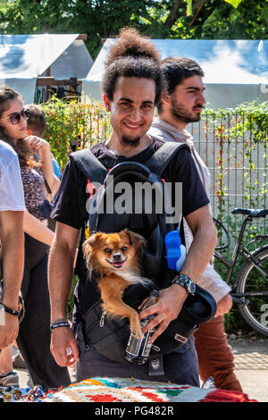 Berlin Mauer Park. Moda giovane con cane nella sacca accanto a stallo del commerciante Foto Stock