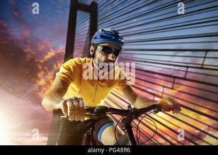 Ciclista ritratto urbano sulla scena notturna durante il tramonto. La moto, natura, bicicletta, sport, ciclo, extreme, lifestyle, avventura e sport concetto con giovani montare uomo caucasico come modello Foto Stock