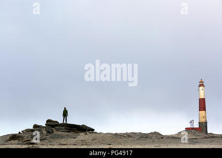 Donna in piedi su una roccia dalla Diaz Point Lighthouse, vicino a Lüderitz, Diamond costa Riserva Naturale, Karas, Namibia Foto Stock