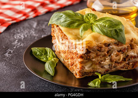 Lasagne tradizionali realizzati con le carni bovine macinate ragù alla bolognese e besciamella guarnita con foglie di basilico. Foto Stock