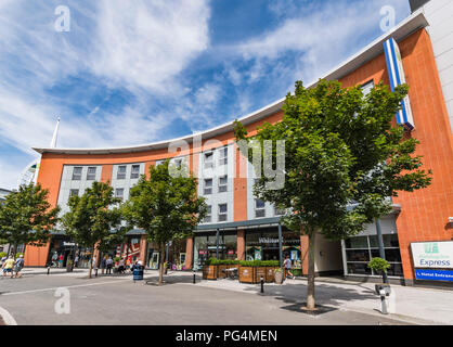 Fila di negozi sotto l'Holiday Inn Express di Gunwharf Quays a Portsmouth, Hampshire, Inghilterra, Regno Unito. Foto Stock