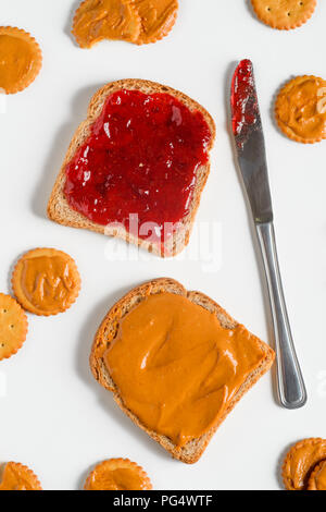 Deliziosi piatti tradizionali di marmellata e burro di arachidi sandwich, top-vista. Coltello, cracker, sfondo luminoso. Foto Stock