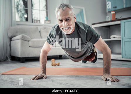 Positivo il piacere senior sportivo facendo push-up Foto Stock