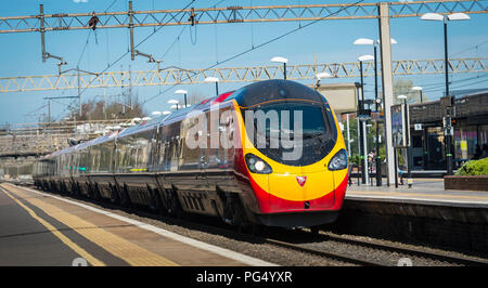 Treni del Virgin pendolino classe 390 electric treno ad alta velocità che arrivano in corrispondenza di una stazione ferroviaria sulla linea di Abbazia, Hertfordshire, Regno Unito. Foto Stock