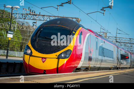 Treni del Virgin pendolino classe 390 electric treno ad alta velocità che arrivano in corrispondenza di una stazione ferroviaria sulla linea di Abbazia, Hertfordshire, Regno Unito. Foto Stock