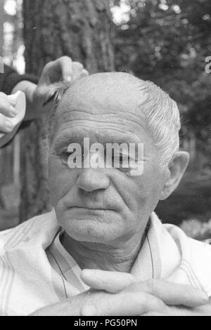 Il scrittore ceco Bohumil Hrabal ottiene il suo taglio di capelli nel giardino della sua casa estiva di Kersko vicino a Praga. Foto Stock