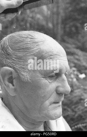 Il scrittore ceco Bohumil Hrabal ottiene il suo taglio di capelli nel giardino della sua casa estiva di Kersko vicino a Praga. Foto Stock