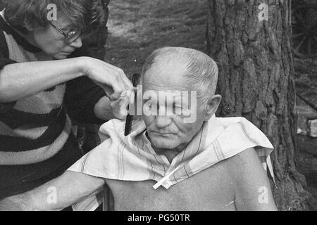 Il scrittore ceco Bohumil Hrabal ottiene il suo taglio di capelli nel giardino della sua casa estiva di Kersko vicino a Praga. Foto Stock
