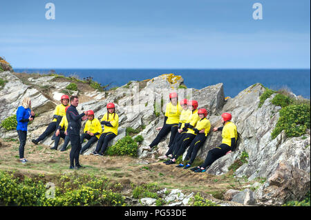 Un istruttore dando un briefing sulla sicurezza a un gruppo di turisti prima di una sessione di coasteering a poco Fistral in Newquay, Cornwall. Foto Stock