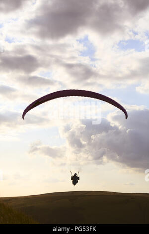 Un parapendio si stagliano contro il cielo sopra Edale Valle del Peak District, Derbyshire. I piloti di sollevamento di guadagno dalla forte corrente ascensionale che occu Foto Stock