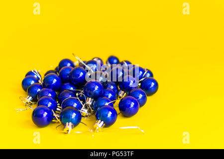 Pila di blu palle di Natale su sfondo giallo Foto Stock