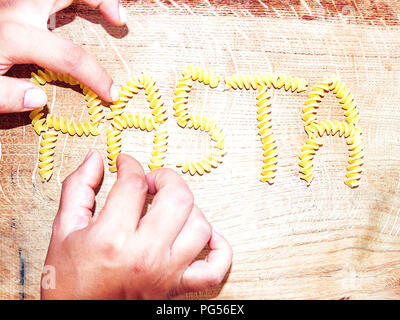 Parola di pasta fatta con pasta fusilli su un tagliere di legno Foto Stock