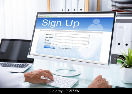 Imprenditore il canto accedendo al sito Web sul computer in ufficio Foto Stock
