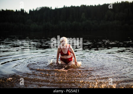 Una donna anziana si diverte a nuotare nel fiume. Foto Stock