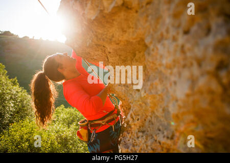 Foto di curly-pelose turista femminile clambering over rock Foto Stock