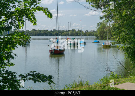 Vista costiera di velieri ormeggiati nel lato lago park sulla bella giornata d'estate. Vista inquadrato attraverso gli alberi e la natura preservare Foto Stock