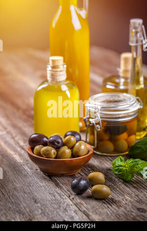 Appena raccolte le olive frutti di bosco in ciotole di legno e olio pressato in bottiglie di vetro Foto Stock