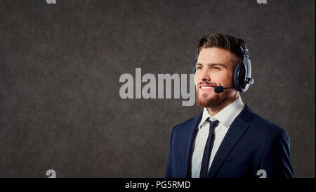 Un maschio di operatore di call center con auricolare su sfondo grigio Foto Stock