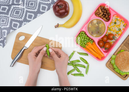 Immagine ritagliata della madre prepara la cena per bambini per la scuola e per l'azienda piselli verdi in pod Foto Stock