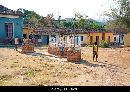 Gli adolescenti cubani a giocare il gioco del calcio sulla massa di rifiuti in Trinidad con casa tradizionale in background Foto Stock