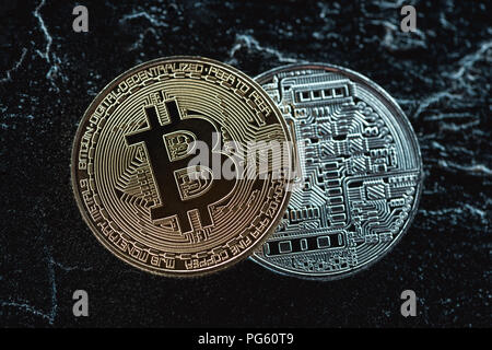 Vista ravvicinata di disposti golden e silver bitcoins scuro sulla superficie di marmo Foto Stock