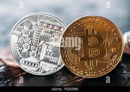 Vista ravvicinata del golden e silver bitcoins sulla superficie scura Foto Stock