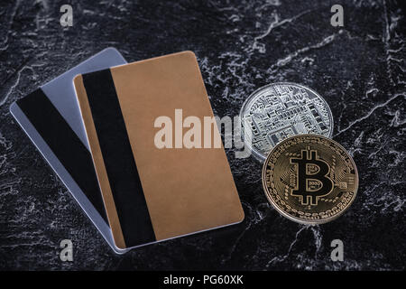 Vista dall'alto di carte di credito e bitcoins scuro sul piano di marmo Foto Stock