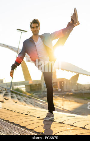 Uomo in equilibrio su una gamba, sorridente Foto Stock