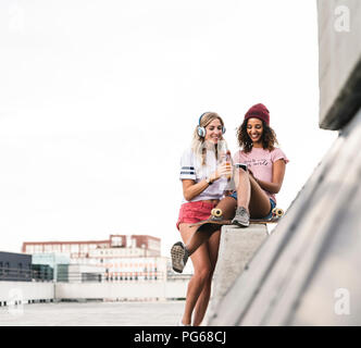 Migliori amici con lo skateboard, divertirsi insieme, ascoltando musica Foto Stock