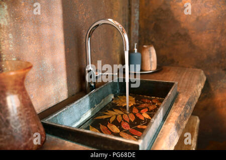 Il lavandino del bagno e acciaio inossidabile tocca nel bagno con acciaio Corten rivestimento a parete Foto Stock