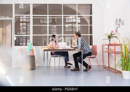 Sorridente colleghi seduti a tavola in un architetto's loft office Foto Stock