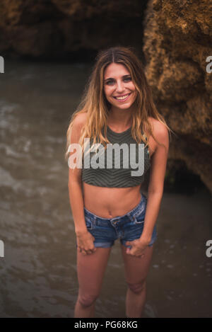 Ritratto di sorridente bella giovane donna in piedi in mare Foto Stock