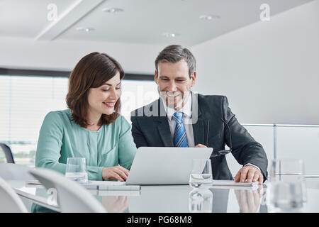 Imprenditore e imprenditrice avente una riunione in ufficio con computer portatile