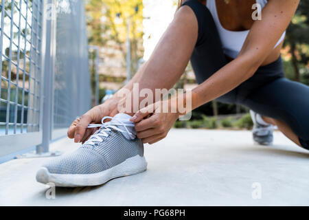 Close-up di donna sportive legando le sue scarpe prima di allenamento Foto Stock