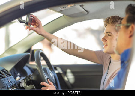 Allievo conducente con istruttore in caradjusting specchio retrovisore Foto Stock