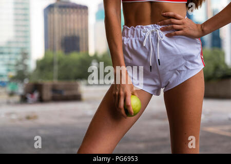 Close-up di giovane donna indossa pantaloncini palestra tenendo un Apple Foto Stock