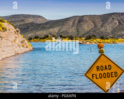 Asfalto allagato sign in strada con una barca a vela in background Foto Stock