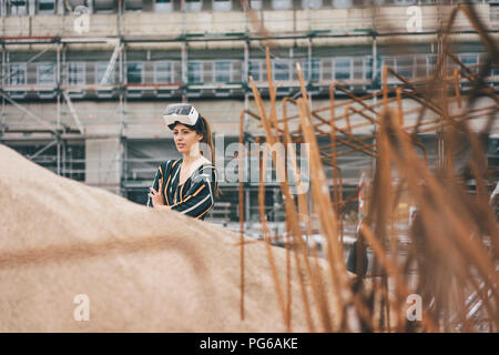 Giovane donna che indossa gli occhiali VR al sito in costruzione Foto Stock